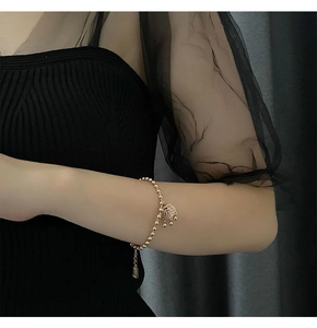 Close-up of a gold-plated beaded bracelet with a vintage Fu character lock pendant