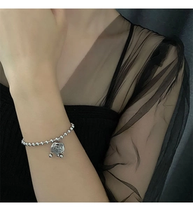 Detailed view of silver bead chain bracelet featuring a vintage Ping An lock charm with Fu character