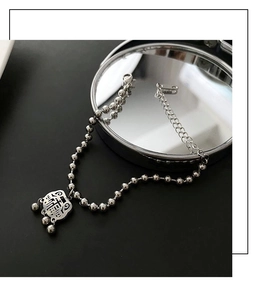 Detail of silver titanium steel bead bracelet featuring a vintage Fu character lock pendant