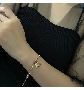 Close-up of gold-plated beaded bracelet with a traditional Chinese lucky lock charm on wrist