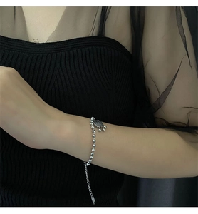 Silver bead bracelet with safe lock pendant and tassel on female model wrist