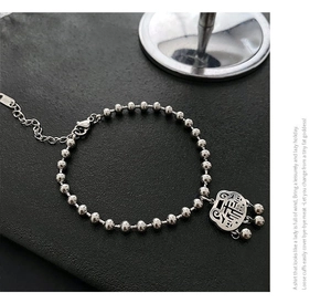 Detailed macro of vintage silver safety lock charm on a beaded titanium steel bracelet