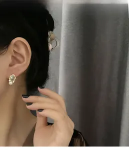 Detail of vintage gold pearl earrings with blue stone and crystals worn by a model