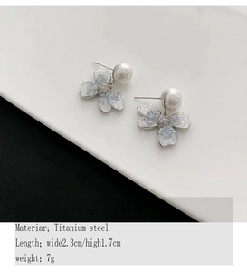 Close-up of titanium steel flower earrings with pearls and blue texture details