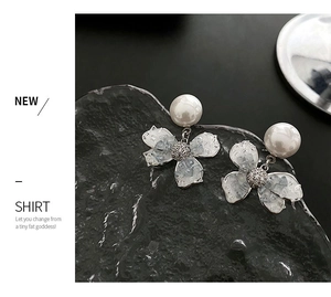Detailed macro view of white floral pearl earrings with subtle crackle glaze and small diamonds