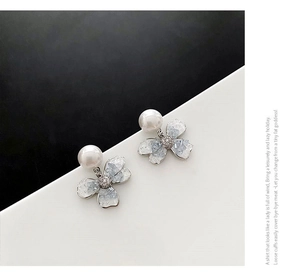 Detail of flower-shaped pearl earrings with light blue marble texture and zircon