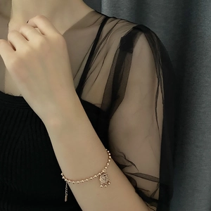 Gold beaded bracelet with an elegant Chinese peace lock pendant on a female wrist