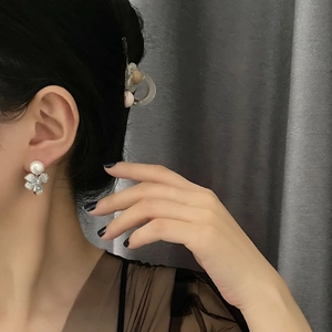 Elegant pearl flower earrings with frosted petals worn by a model on dark background