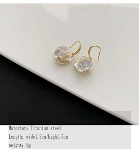 Detail shot of white camellia earrings in titanium steel with gold flower hooks