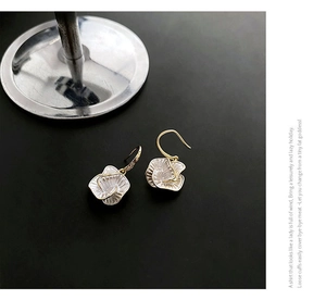 Macro detail of camellia flower earrings with white petals and elegant gold plating