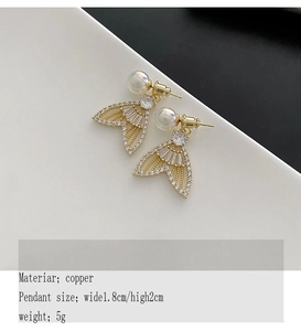 Detail view of gold fishtail earrings with pearl and cubic zirconia, 1.8cm by 2cm size