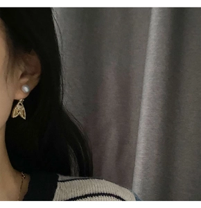 Detail showing the micro-set butterfly pendant and pearl drop earring on model