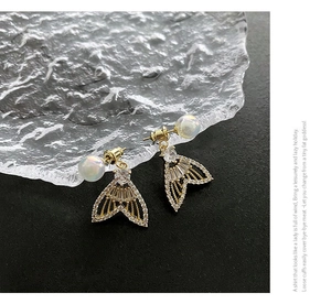 Macro shot of fishtail drop earrings with micro-set zircon and iridescent pearl details