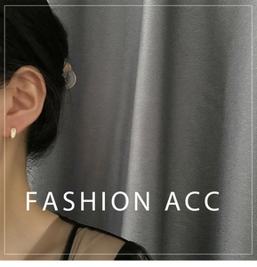 Gros plan d'une boucle d'oreille dorée avec émail jaune portée par un mannequin femme