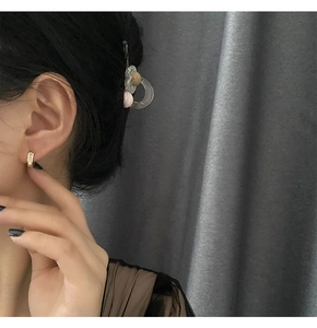 Gros plan d'une boucle d'oreille minimaliste en forme de U dorée portée par un modèle