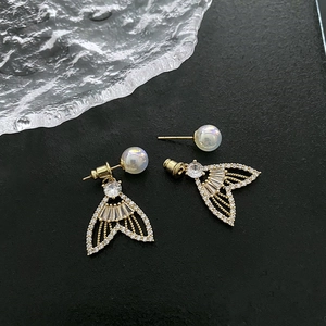 Elegant fishtail drop earrings in gold with pavé crystals and white pearls on black background
