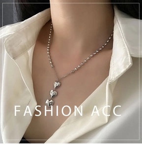 Détail du collier argenté avec pendentif triple cœurs et chaîne à boules
