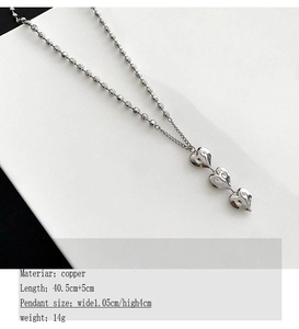 Vue détaillée du triple pendentif cœur sur une chaîne à billes argentée avec mesures