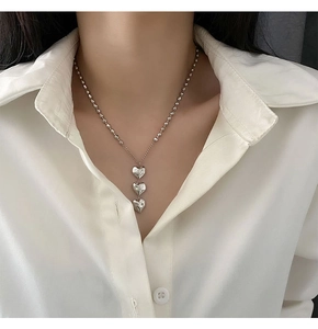 Détail d'un collier à billes argenté avec trois pendentifs en forme de cœur poli sur modèle