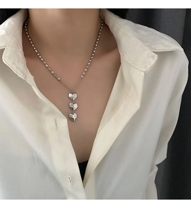 Détail du collier à pendentif cœur argenté sur modèle montrant le design à trois cœurs