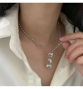 Détail du collier argenté à triple pendentif cœur avec chaînes à billes sur modèle