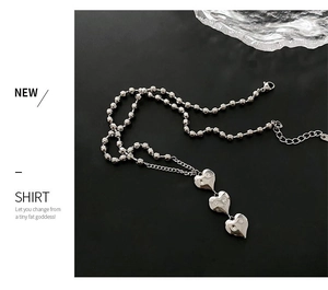 Vue détaillée du collier à pendentif cœur et pompon argenté sur un fond noir élégant
