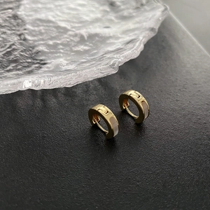 Élégantes boucles d'oreilles créoles dorées avec émail blanc sur fond texturé