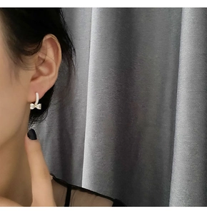 Nahaufnahme eleganter Schleifenohrringe mit Zirkoniasteinen am Modell getragen
