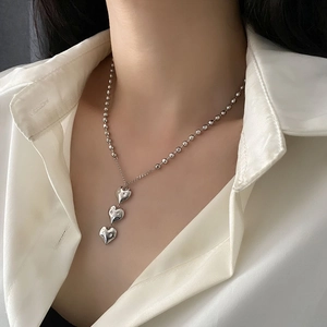 Collier chaîne à perles argentées avec triple pendentif cœur sur un mannequin