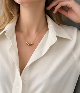 Close-up of gold beaded pendant necklace on female model with delicate chain detail
