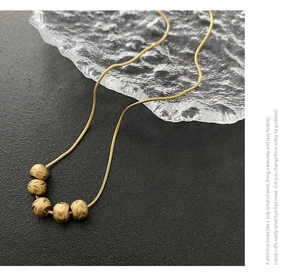 Detail of vintage gold necklace with five brushed beads on a sleek snake chain