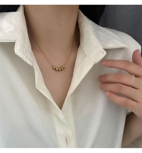 Detail of gold bead pendant necklace on woman wearing a white professional shirt
