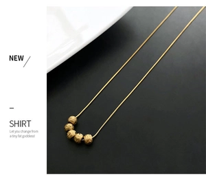 Detailed macro view of vintage gold necklace with five textured beads on a snake chain
