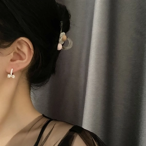 Elegante Zirkon-Bogenohrringe und Haarspange mit Perlen an einem weiblichen Modell