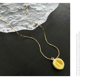 Gros plan du collier pendentif durian doré sur cuir noir et verre à ondes d'eau