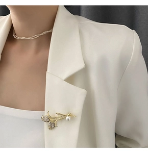 Détail d'une broche tulipe de luxe avec strass et perle sur le revers d'un blazer blanc