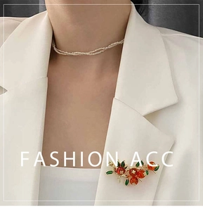 Gros plan d'une broche kaki vintage avec feuilles vertes sur un blazer blanc
