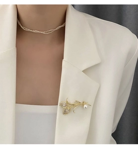 Détail de la broche tulipe de luxe avec zircone et perle sur un blazer blanc