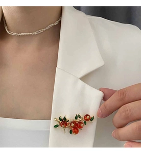 Vue détaillée d'une broche vintage aux baies rouges sur le revers d'un costume blanc