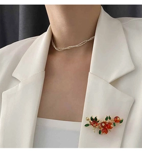 Détail d'une broche vintage en alliage doré avec des feuilles en émail élégantes