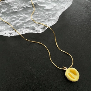 Collier avec pendentif durian créatif et chaîne dorée sur fond noir texturé