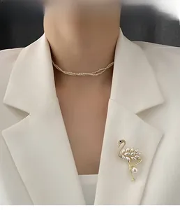 Detail of flamingo brooch with white faux pearls worn on a white blazer lapel