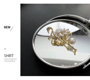 Detailed close-up of golden flamingo brooch with pearl wings and crystal accents