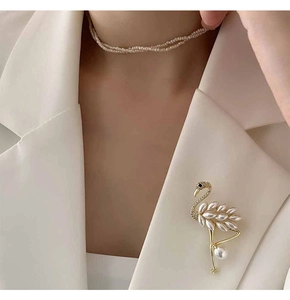 Detail of flamingo brooch with pearls and zircon on a cream suit jacket