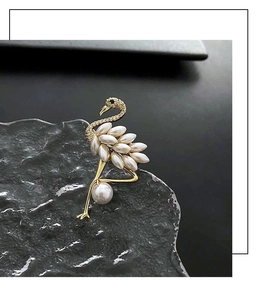 Close-up of golden flamingo brooch with pearls and rhinestones on dark stone