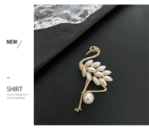 Detailed view of elegant flamingo brooch with white faux pearls and crystals on black background