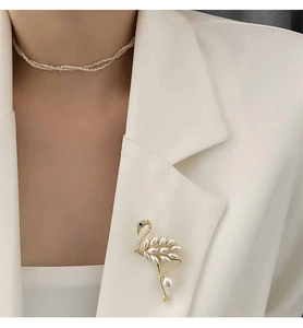 Close-up of elegant flamingo brooch with pearls pinned to a white blazer lapel