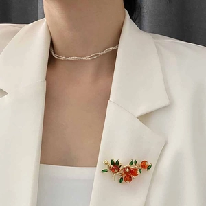 Broche branche de persimmon élégante avec baies orange sur un revers de veste blanc