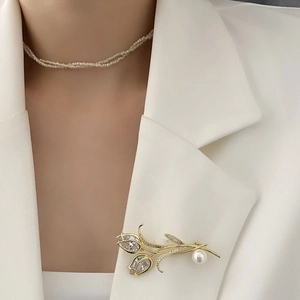 Élégante broche tulipe dorée avec zircons brillants et perle blanche sur un blazer blanc