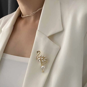 Elegant gold flamingo brooch with white pearls and crystals on a blazer lapel